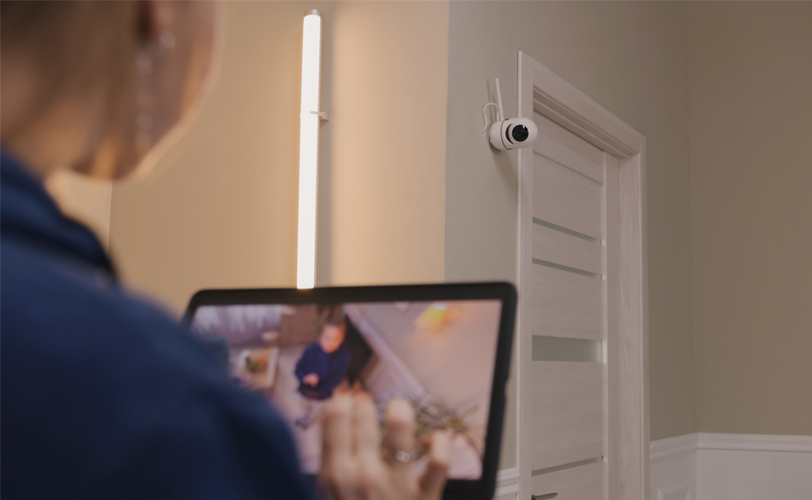 Woman using an iPad to view CCTV footage inside her home.