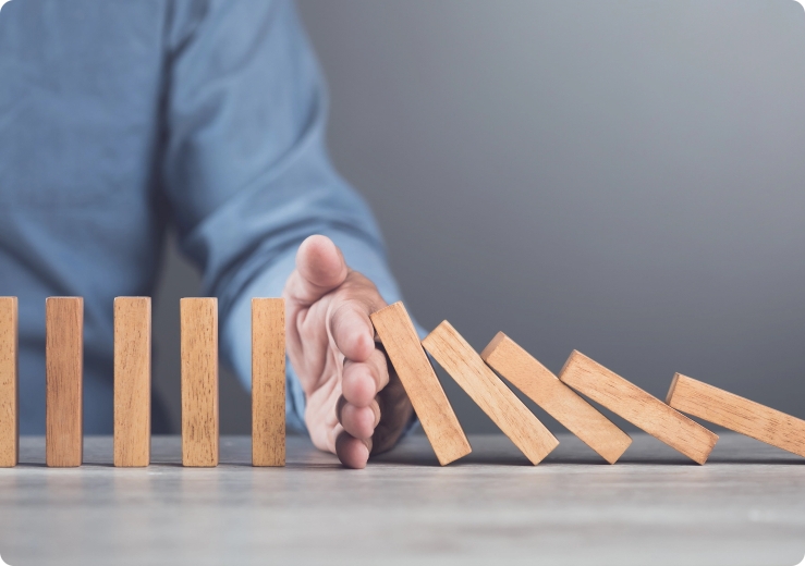 image of hand stopping wooden domino blocks from falling symbolising intervention