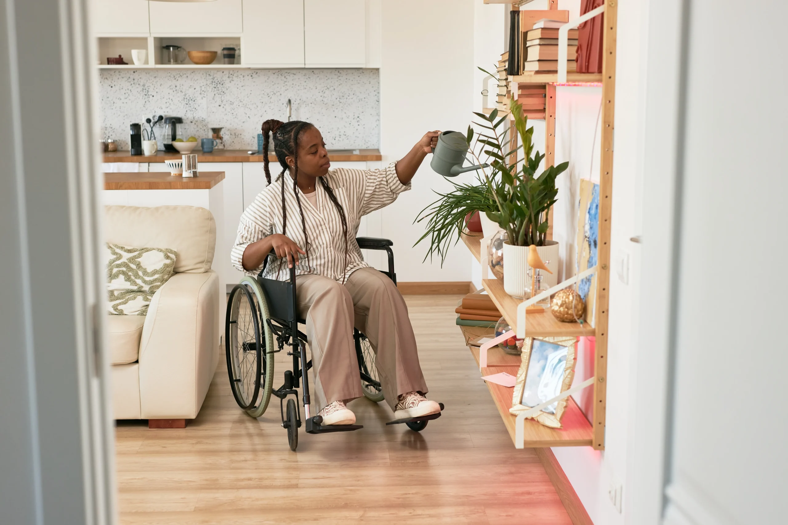 Afro-Caribbean disabled woman watering plants on a lowered shelf
